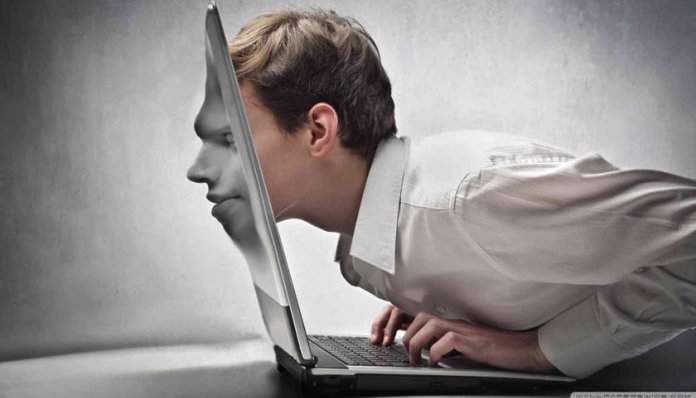 Imagem mostra um rapaz um homem trespassando o rosto pela tela de um notebook.